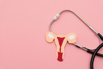 Stethoscope with uterus cutout on pink background representing women's health