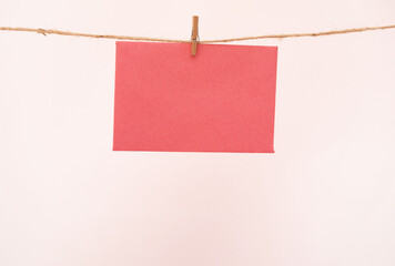 Red Blank Paper Hanging on a String with Clothespin - copy space for Announcement or Message Concept on light Background