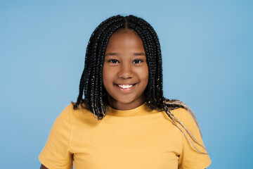 Cute smiling African American girl with stylish hair wearing casual t shirt looking at camera