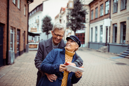 Senior couple laughing and exploring city with a map