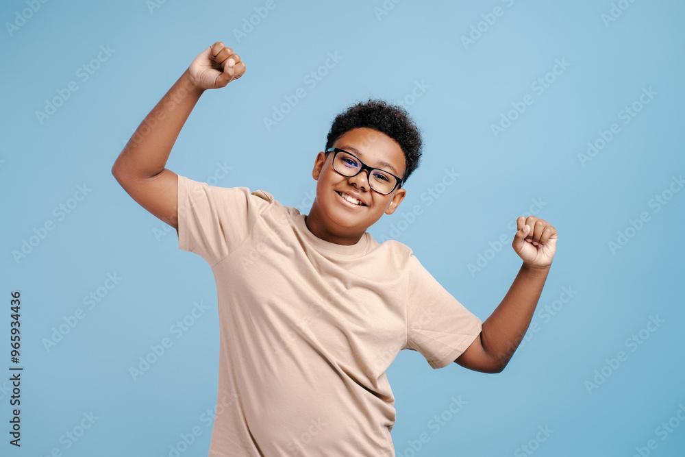 Wall mural portrait of smiling boy wearing glasses making winner gesture, looking at camera