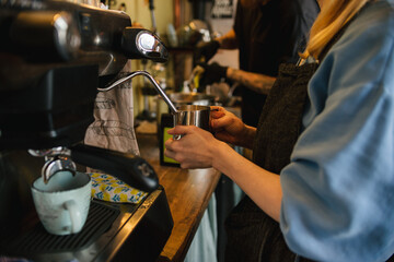Girl is making Coffee at the coffee machine. Milk whisp for Latte. Coffee latte with Milk. Coffee shop