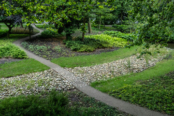 A beautifully designed garden featuring curving pathways and various lush foliage, inviting a sense...