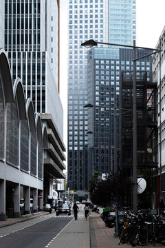 An urban scene portraying a pedestrian-friendly street surrounded by towering buildings, streetlife, and parked bicycles, demonstrating the hustle and bustle of city life in Rotterdam