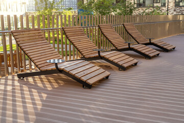 Four wooden lounge chairs with slatted design placed on a sunny deck, inviting relaxation in a serene outdoor setting