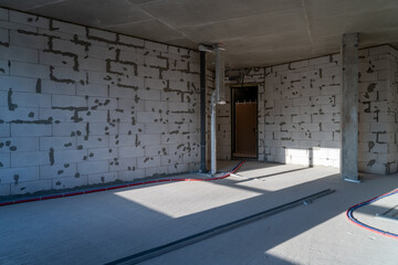 The interior space features bare walls with cement blocks, unfinished flooring, and visible electrical conduits, highlighting construction progress