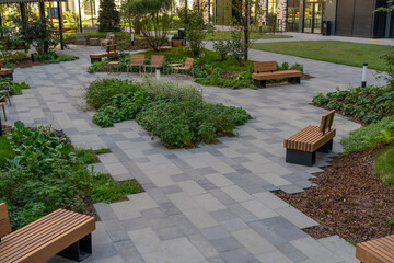 A peaceful garden with wooden benches surrounded by lush plants and pathways in an urban environment on a sunny day