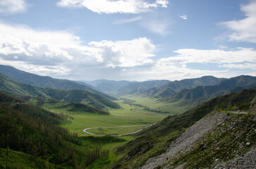 Mesmerizing panorama serpentine road running through hills and glades. beautiful day in nature among greenery and cloudy sky. Background for text or banner photo Hight quality