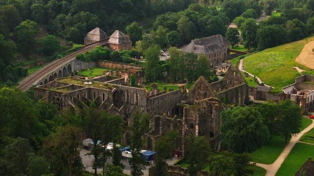 Tourists enjoy a sunny day a Villers La Ville Abbey, historic ruins set against a backdrop of lush green forests and stunning ancient architecture