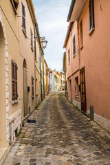 Obraz premium A view up the narrow main street in the hilltop fortress village of Sant Andrea di Suasa, Italy in summertime