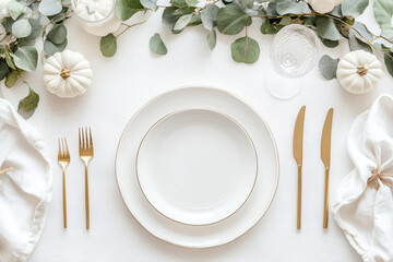 Decorated table featuring white pumpkins, eucalyptus leaves, and candles
