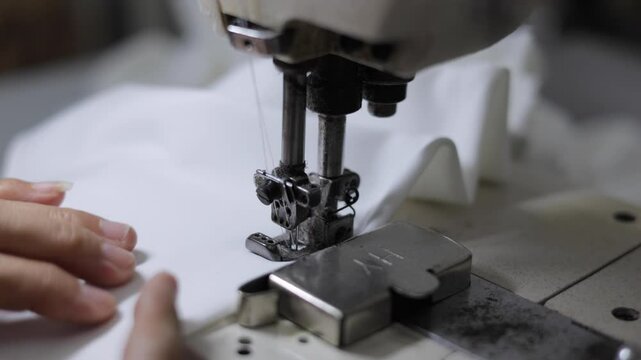 Sewing machines are working, producing clothes in a factory.
