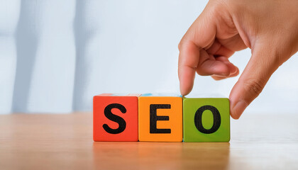 A hand is touching a block of wood with the letters SEO on it