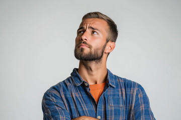 Fototapeta premium A portrait of a man or male thoughtfully pondering a problem against a soft light background. For question, teaser, and problem-solving concepts.
