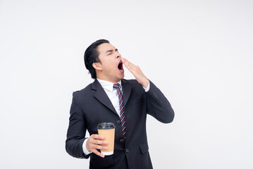 A tired young asian business executive yawning while holding a cup of coffee. Isolated on a white background.