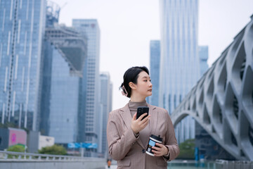 Stylish Young Woman Utilizing Mobile Device in Modern Urban Setting