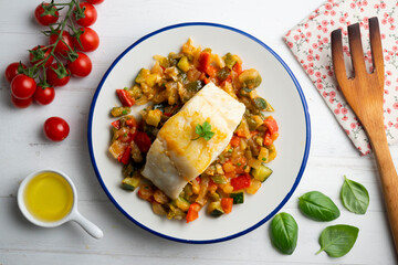 Cod with baked vegetables traditional Spanish recipe. Top view food.