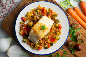Cod with baked vegetables traditional Spanish recipe. Top view food.