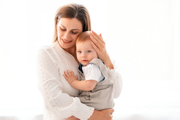 a mother with a child, a young mother gently hugs and kisses her little son at home on a white isolated background, maternal love and care, a happy decree, a mother and a little boy, a place for text