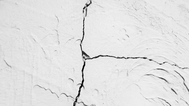 Cracked plaster. Cracks in the wall. Damaged gray, white plaster. Cracks on the wall close up