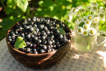 Fresh Blackcurrants in a Wooden Bowl with Wildflowers
