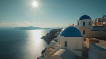Fototapeta premium A high-angle view of the Orthodox Church in Oia, Santorini, with its blue dome shining in the sunlight, and the village and sea extending into the horizon