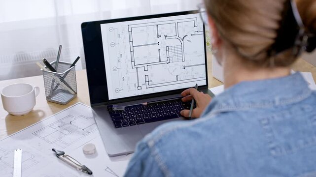 Interior drawings on a laptop screen. An architect designer develops sketches of a house. Construction project blueprint.