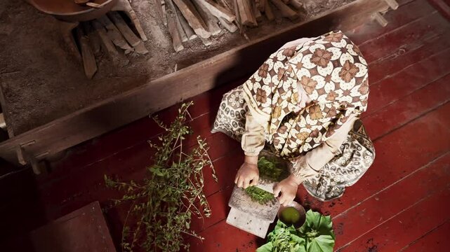 An Asian woman grinds leaves from the henna tree to make henna paste