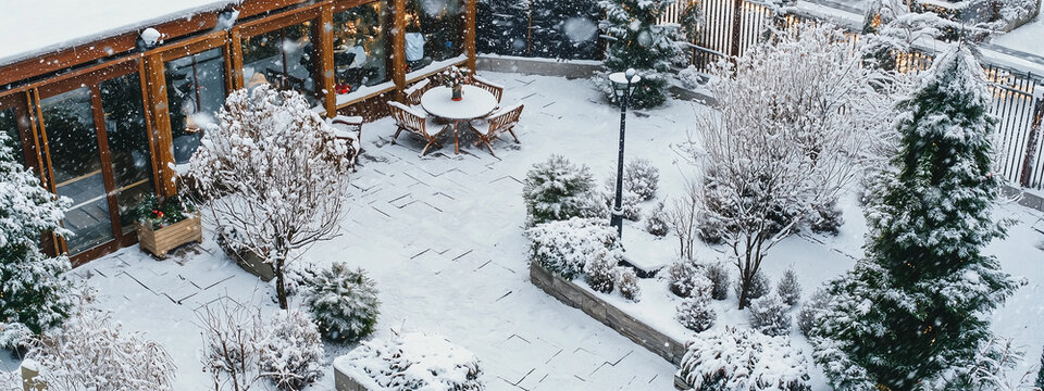 Serene winter back garden blanketed in snow, showcasing frosted trees and a tranquil fountain.