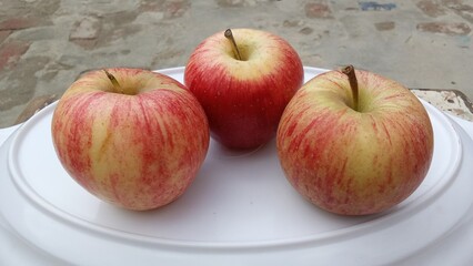three fresh red apples on a plate