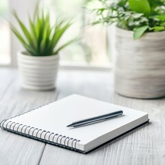 A minimal workspace featuring a blank notebook and a pen beside decorative plants, ideal for inspiration and creativity.