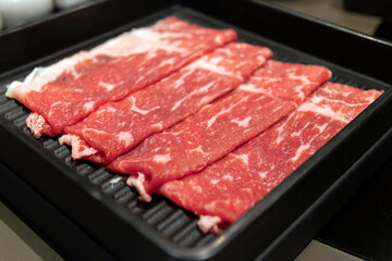 Freshly sliced beef arranged neatly on a grill plate.