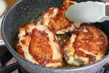 Juicy and crispy chicken thighs frying in a skillet, showcasing golden-brown perfection and delicious texture.