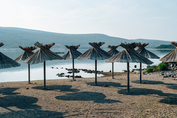 Beach with straw umbrellas. Beautiful summer seascape of Adriatic sea, Punat town, Krk island, Croatia