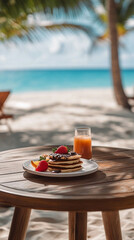Vertical photo of Pancakes with chocolate sauce and strawberries next to fresh tropical juice on a wooden table with the Caribbean sea view. Perfect breakfast at the beach