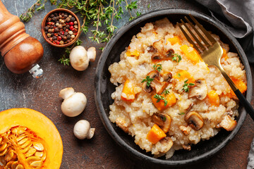 Pumpkin mushrooms risotto with fresh thyme in ceramic bowl. Italian Cuisine. Top view
