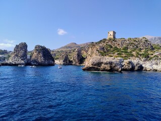 Blue waters in Sicily island. Boat trip around the sicilian coast. Italian life. Summer in Europe. Ancient fortress over the clear sea. Ocean landscape with cliffs. Smell of lemons, grapes and olives.