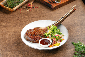 Portion of grilled tomahawk steak with salad and sauce