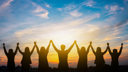 Group of People Standing with Raised Hands in Unity and Joy under Beautiful Sunset Sky, Celebrating Together