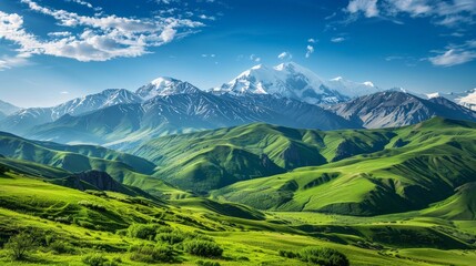 A mountain landscape with green valleys and snow-capped peaks under a clear, bright summer sky