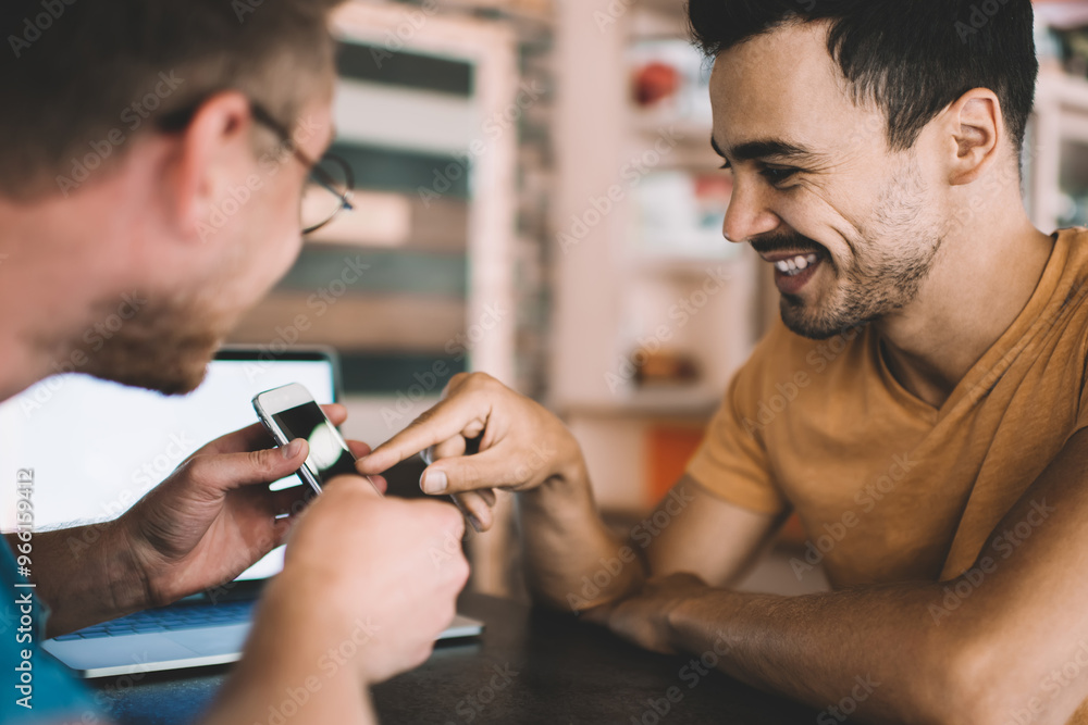 Aufkleber happy male bloggers discussing notification for application on smartphone gadget sitting at table an
