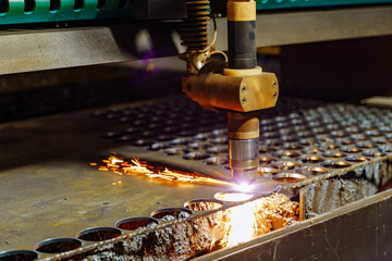 Laser cutting metal parts in a manufacturing facility at night. A laser cutter shapes metal...