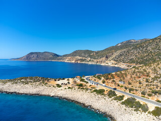 View of road along coast from drone. Travelling by car in summer. Aerial view of mountain road near blue sea Beautiful landscape with highway, cliffs, sea coast