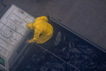 A city sanitation worker in a yellow raincoat walks over waste.