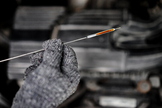 Close-up of the oil dipstick in the mechanic's hand to check the level of the engine oil. Car repair and maintenance concept