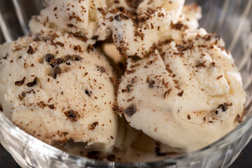 white creamy ice cream with pieces and crumbs of chocolate in a glass bowl