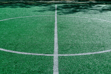 Obraz premium The marking of the center of the soccer stadium. Empty soccer field with an artificial green turf