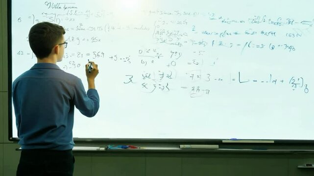 Student solving complex math equations on a whiteboard in modern classroom during evening study session