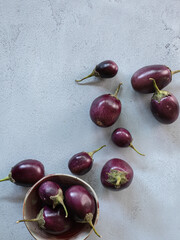Baby eggplants scattered on a gray table.