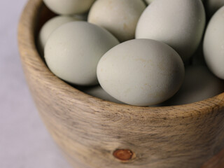 Close up view of fresh eggs in a wooden bowl.